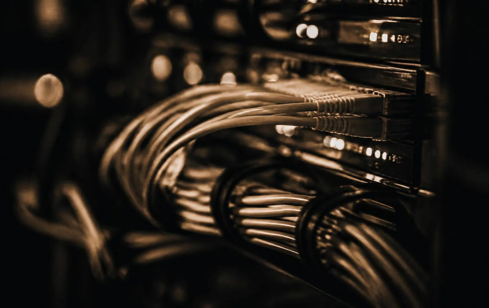 Close-up of structured network cabling inside a server rack, lit in warm amber light